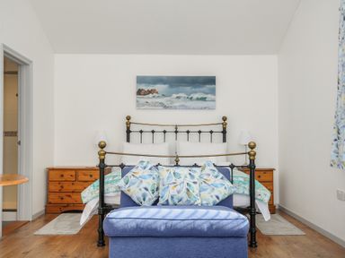A bedroom with a metal bed frame a blue cushioned bench and wooden bedside tables at Lambley View in Bude