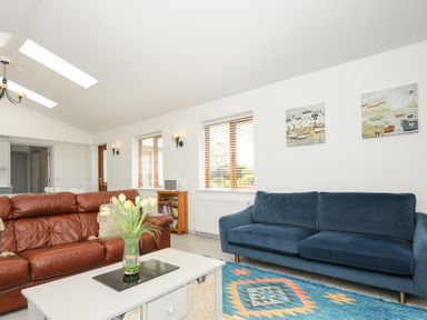 A living room with two sofas a coffee table with flowers a rug and paintings on the wall at Lambley View in Bude