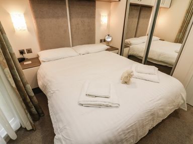 A bedroom with a bed with white linens towels and a stuffed animal on the bed at 3 Yealands in Carnforth