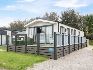 An exterior view of a mobile home with a deck and outdoor furniture at 3 Yealands in Carnforth
