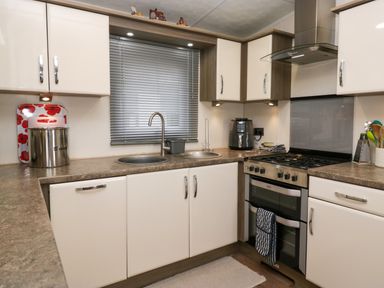 A kitchen with a double sink a gas stove with oven and cabinets at 3 Yealands in Carnforth