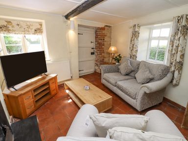 A living room with a sofa armchair wooden coffee table and television on a wooden stand at 5 Packhorse in Purton