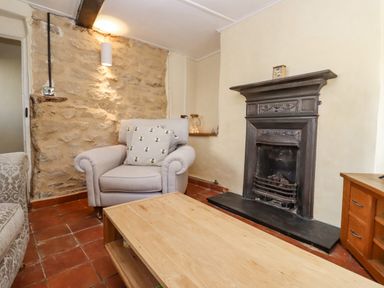 A living room with a stone wall armchair wooden coffee table and fireplace at 5 Packhorse in Purton