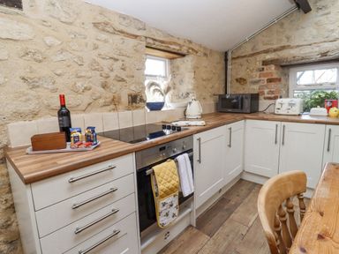 A kitchen with white cabinets wooden countertops a stove oven microwave and toaster at 5 Packhorse in Purton