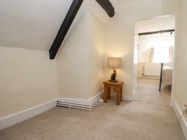 A small hallway with a wooden side table and a lamp leading to a bedroom at 5 Packhorse in Purton