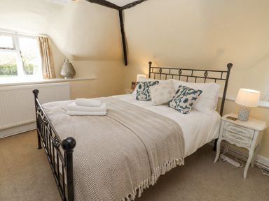 A bedroom with a metal bed frame pillows a blanket and bedside tables with lamps at 5 Packhorse in Purton