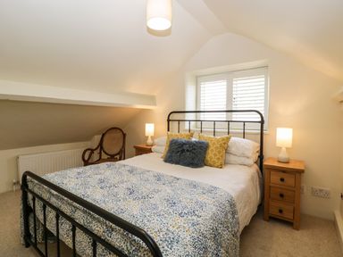 A bedroom with a metal bed frame bedside tables with lamps and a wooden chair at The Hayloft in Stockland Honiton
