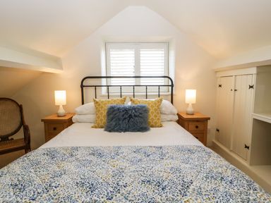 A bedroom with a bed with pillows and blankets and bedside tables with lamps at The Hayloft in Stockland Honiton