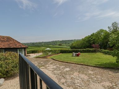 An outdoor garden area with a cobblestone path green lawn and outdoor furniture at The Hayloft in Stockland Honiton