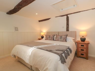 A bedroom with a double bed bedside tables lamps and exposed wooden beams at The Hayloft in Stockland Honiton