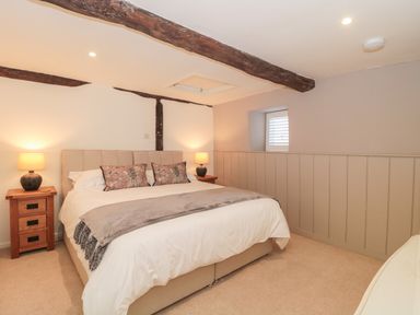 A bedroom with a bed with cushions and a throw and two bedside tables with lamps at The Hayloft in Stockland Honiton