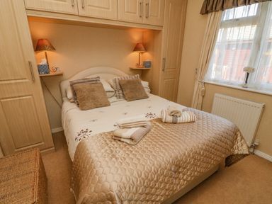 A bedroom with a double bed cushions bedside lamps and folded towels on the bed at Mallard Lodge in Carnforth