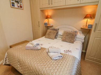 A bedroom with a bed pillows lamps and towels at Mallard Lodge in Carnforth