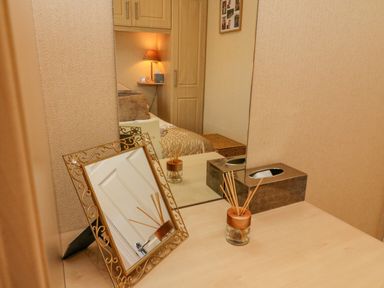 A bedroom vanity table with a decorative mirror reed diffuser and tissue box at Mallard Lodge in Carnforth