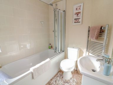 A bathroom with a bathtub shower combination toilet sink and towel rack at Mallard Lodge in Carnforth