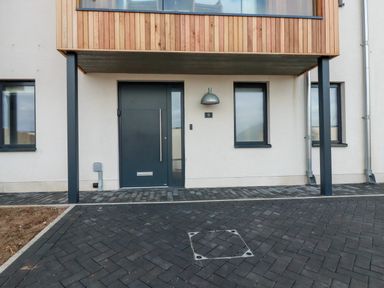 A modern house entrance with a dark door and two windows at Porth Beach Villa in Porth near Newquay