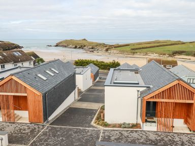 Modern residential buildings near a beach with grassy hills in the background at Porth Beach Villa in Porth near Newquay