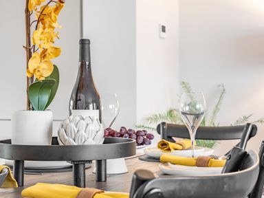 A dining table set with wine bottle grapes and yellow napkins at Porth Beach Villa in Porth near Newquay