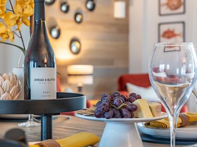 A table setting with a bottle of bread and butter pinot noir wine and a plate with grapes and cheese at Porth Beach Villa Porth near Newquay