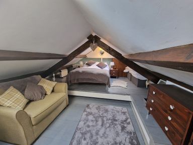 An attic bedroom with a bed sofa rug and chest of drawers at Quarry Cottage in Blaenau Ffestiniog