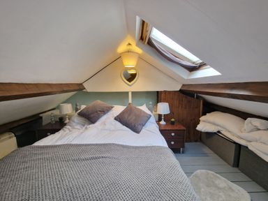 A bedroom with a double bed two pillows bedside tables lamps skylight window and folded bedding at Quarry Cottage in Blaenau Ffestiniog
