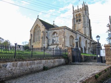 An old stone church with arched windows a tower and iron gate at the entrance