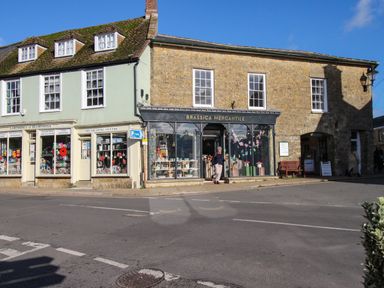 A street view of shops including Larcombes of Beaminster and Brassica Mercantile in Beaminster