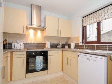 A kitchen with an oven stovetop hood cabinets toaster kettle and dishwasher at St Albans in Boscastle