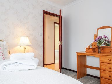 A bedroom with a bed white towels a lamp wooden dressing table with mirror and flowers at St Albans in Boscastle