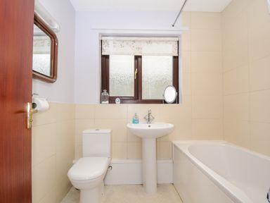 A bathroom with a toilet sink bathtub and a window with a floral blind at St Albans in Boscastle