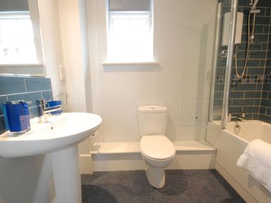 A bathroom with a sink toilet and bathtub with shower at Crabbe Corner in Aldeburgh