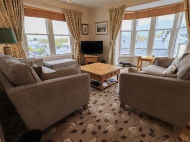 A living room with two sofas a wooden coffee table a television and large windows at Peak View in Keswick