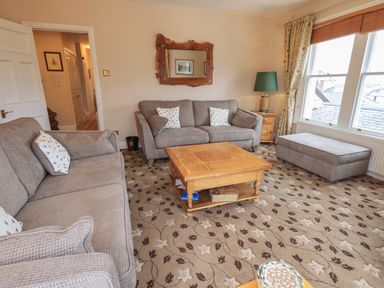 A living room with two sofas a wooden coffee table a lamp and large windows at Peak View in Keswick