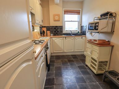 A kitchen with white cabinets black tiled backsplash and window at Peak View in Keswick