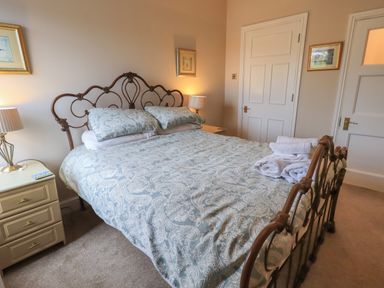 A bedroom with a double bed with patterned bedding and towels on it two bedside tables with lamps and framed pictures on the walls at Peak View in Keswick
