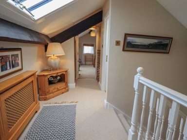 A hallway with a wooden side table and lamp under a slanted ceiling with skylight at Peak View in Keswick