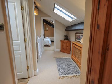 A hallway with a skylight rug and wooden furniture leading to a bedroom at Peak View in Keswick