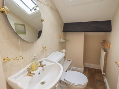 A small bathroom with a sink toilet mirror and wooden floor at Peak View in Keswick