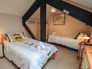 A bedroom with two beds and a wooden beam with a mind your head sign at Peak View in Keswick