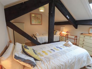 A bedroom with two single beds wooden beams a chest of drawers and a nightstand at Peak View in Keswick