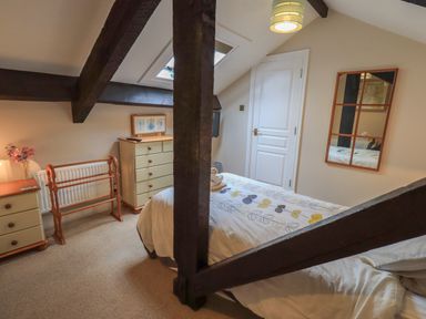 A bedroom with a bed dresser mirror and wooden beams at Peak View in Keswick