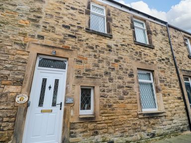 The exterior of a stone building with white doors and windows at Bonnies Retreat in Amble