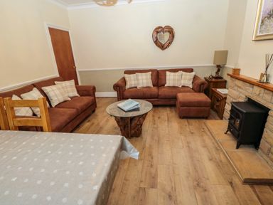 A living room with two sofas a wooden heart-shaped wall mirror a coffee table and a fireplace at Bonnies Retreat in Amble