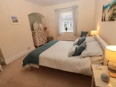 A bedroom with a bed multiple pillows lamps and a dresser with a mirror at Bonnies Retreat in Amble