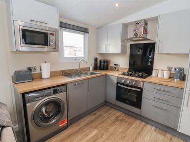 A kitchen with microwave toaster washing machine oven and stove at 24 Sherwood in Carnforth