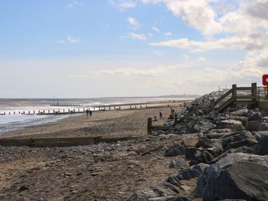 A beach with people walking on sand and rocks near the sea at Church View in Atwick