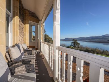 A balcony with chairs overlooking water and mountains at Bryn Mel Manor Straits View Menai Bridge