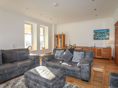 A living room with gray sofas a wooden cabinet and an ottoman at Bryn Mel Manor Straits View Menai Bridge