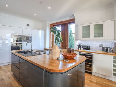 A modern kitchen with an island counter a sink and wooden countertops at Bryn Mel Manor Straits View in Menai Bridge