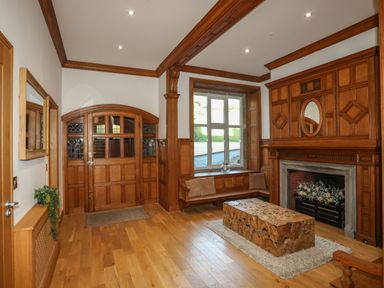 A room with wooden paneling a fireplace a bench with cushions a wooden coffee table and a window at Bryn Mel Manor Straits View Menai Bridge